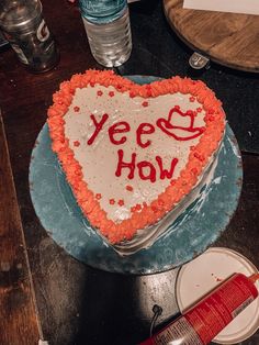 a heart shaped cake with the words yeee how written on it, sitting on a table