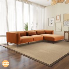 an orange sectional sofa sitting on top of a wooden floor next to a large window