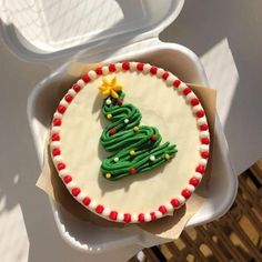 a decorated christmas cake sitting on top of a white plate next to a plastic container