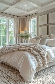 a large white bed sitting in a bedroom next to two windows and a rug on the floor