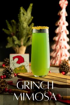 a green drink sitting on top of a table next to pine cones and christmas decorations