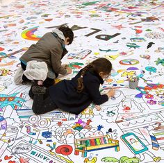 two children are sitting on the floor drawing