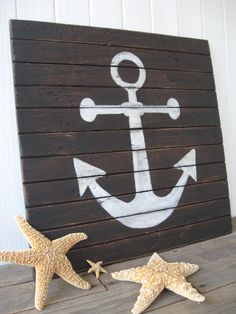 two starfish and an anchor painted on wood planks next to a wooden sign