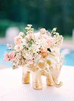 an elephant vase filled with flowers on top of a table