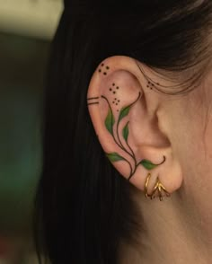 a close up of a person's ear with tattoos on it