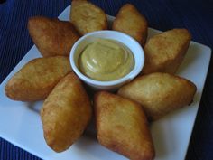 some fried food on a white plate with a dipping sauce in the middle and blue cloth