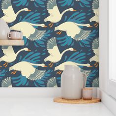 two mugs are sitting on a shelf in front of a wallpaper with geese