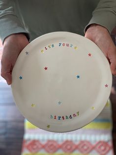 a person holding a white plate with stars on it that says, keep your birthday