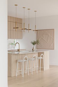 a kitchen with an island, bar stools and gold fixtures on the countertop