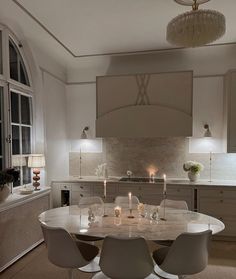 a table with four chairs around it in the middle of a living room and kitchen