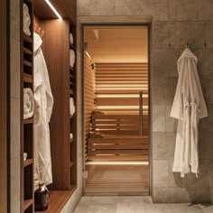 there is a sauna in the bathroom with towels hanging on the wall and two robe racks