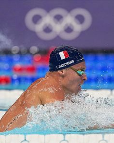 a man swimming in a pool wearing a hat and goggles with the flag of france on it