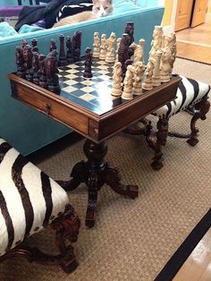 a chess set sitting on top of a wooden table next to a zebra print chair