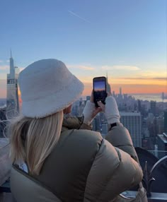 a woman taking a photo with her cell phone in new york city's skyline