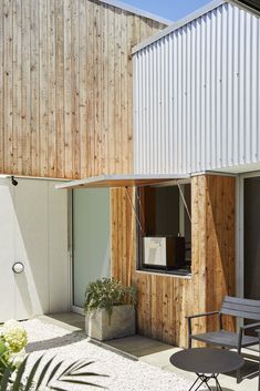 an outdoor patio with chairs and tables next to a building that has corrugated siding on it