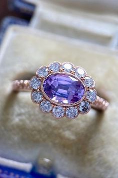 an engagement ring with a purple stone surrounded by diamonds