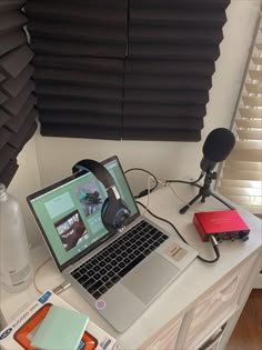 an open laptop computer sitting on top of a desk next to a microphone and headphones