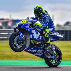 a man riding on the back of a blue and green motorcycle down a race track