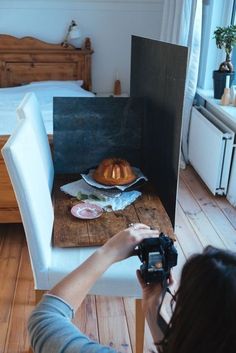 a woman taking a photo of food on a table with a camera in front of her