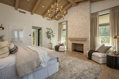 a large bed sitting in a bedroom under a chandelier next to a fire place