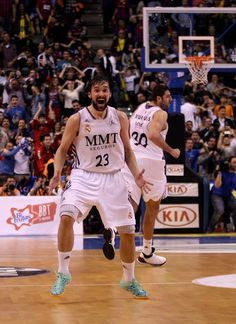 two men playing basketball in front of a crowd with people watching from the sidelines