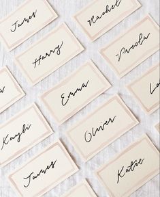 many different types of name cards on a white tablecloth with black ink and some type of writing