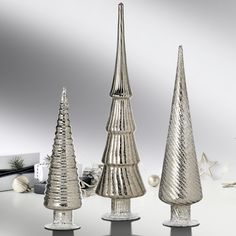 three silver christmas trees sitting on top of a table