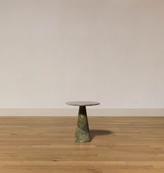 a small round table sitting on top of a wooden floor next to a white wall