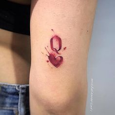 a woman's thigh with a heart tattoo on her left leg and the letter q painted in red ink