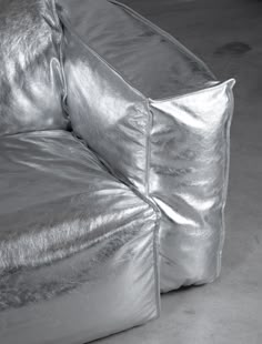 a shiny silver couch sitting on top of a white floor