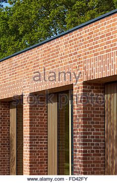 the side of a brick building with shutters and trees in the background