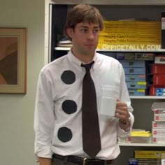 a man in a white shirt and black tie holding a cup with a face painted on it