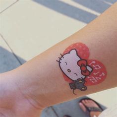 a hello kitty tattoo on the arm of a woman's arm with a heart