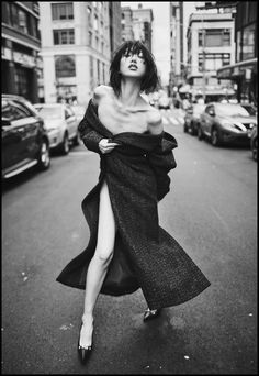 a woman is walking down the street with her leg in the air while wearing a long dress