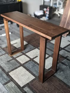 a wooden bench sitting on top of a carpeted floor next to a chair and table