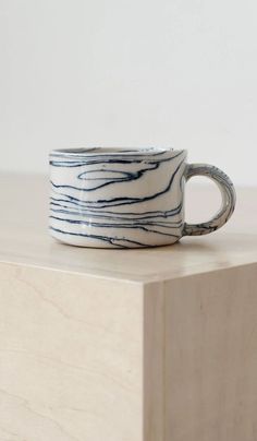 a white and blue coffee cup sitting on top of a wooden table