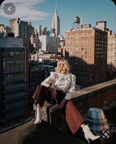 a woman sitting on top of a roof next to tall buildings