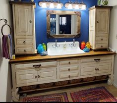 a bathroom with blue walls and wooden cabinets, rugs and lights on the vanity