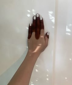 a woman's hand on the wall with sunlight shining through her fingers and nails