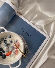 a bowl of oatmeal with blueberries and strawberries in it next to a cup of coffee