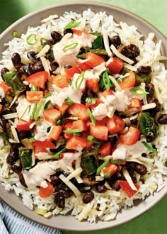 a bowl filled with rice, beans and other vegetables on top of a green table