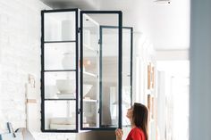 a woman standing in front of a refrigerator with its door open and she is looking at it