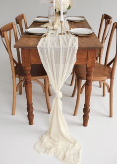 the table is set with white flowers and place settings for four people to sit at