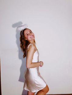 a young woman in a white dress posing for a photo with her hands on her hips