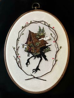 the embroidery is hanging on the wall and has a bird in it's hand