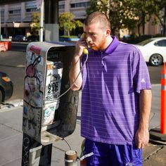 a man standing next to a parking meter talking on a cell phone