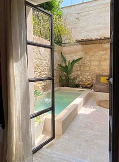 an open door leading to a small pool in the middle of a room with windows