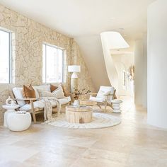 a living room filled with lots of furniture next to tall windows on top of a stone wall