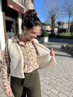 a woman is walking down the street with her hand in her pocket and wearing green pants