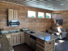 a kitchen and living room with wood paneling on the walls, counter tops and appliances